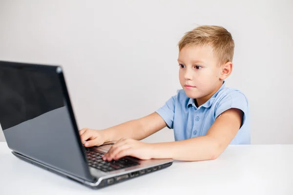 Blond pojke tittar på laptop Stockbild