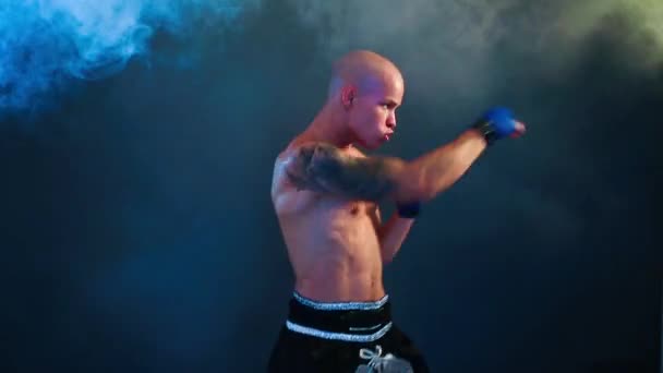Muscular kickbox or muay thai fighter punching in smoke. — Stock Video