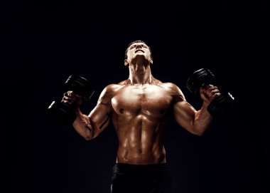 Kaslı adam dumbbells ile egzersiz yaparak konsantre