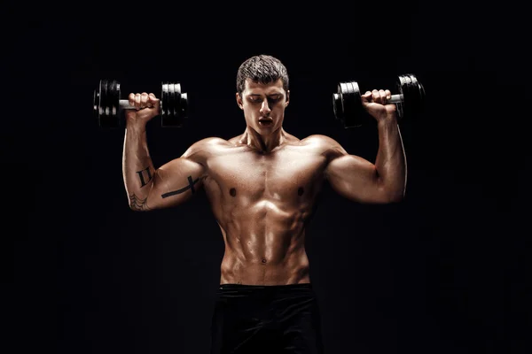 Концентрированный мускулистый человек делает упражнения с гантелями — стоковое фото