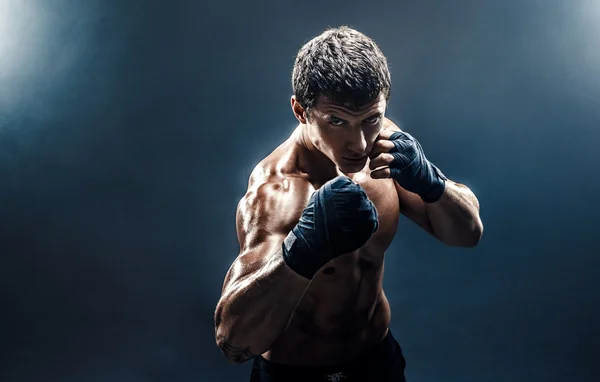 Muscular kickbox ou muay thai lutador perfurando na fumaça . — Fotografia de Stock