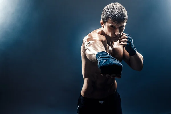 Muscular kickbox o muay thai luchador puñetazos en el humo . — Foto de Stock