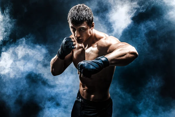 Muscular kickbox ou muay thai lutador perfurando na fumaça . — Fotografia de Stock