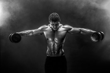 Kaslı adam dumbbells ile egzersiz yaparak konsantre