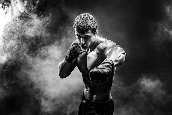 Studio portrait of fighting muscular man in smoke.