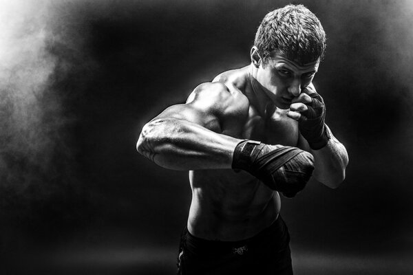 Studio portrait of fighting muscular man in smoke.