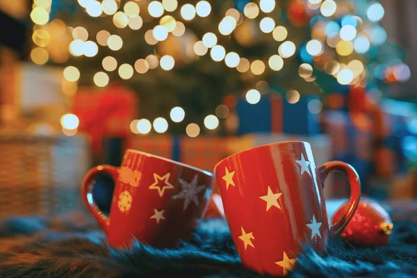 Dos tazas cerca del árbol decorado con Navidad, fondo borroso —  Fotos de Stock