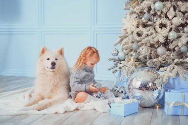 Evde köpeğiyle Noel ağacı süsleyen tatlı bir kız.