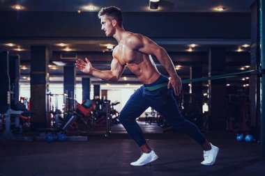 Genç bir sporcu direniş bandıyla egzersiz yapıyor.