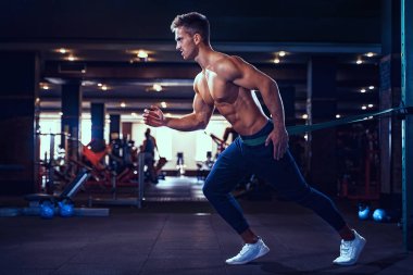 Genç bir sporcu direniş bandıyla egzersiz yapıyor.