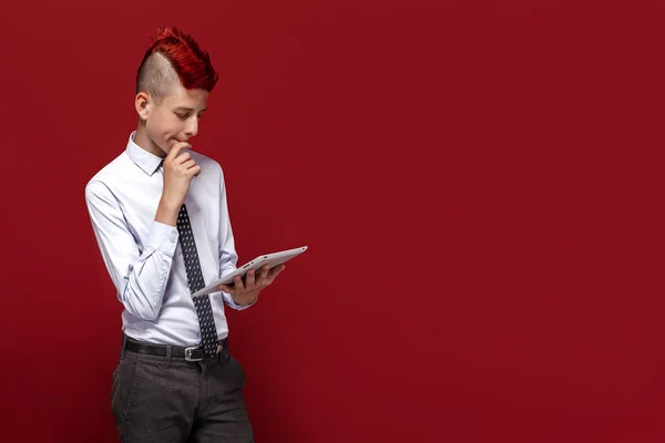 Punk elegante com tablet contra de fundo vermelho — Fotografia de Stock