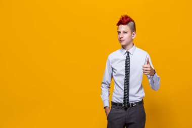 İzole edilmiş sarı arka planı olan genç bir çocuk elleriyle olumlu bir jest yapmayı onaylıyor, gülümsüyor ve başarı için mutlu. Kazanan jest