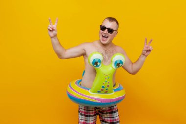 Sarı arka planda salyangoz ve güneş gözlüğü şeklinde lastik halkalı üstsüz bir adam. İzole et