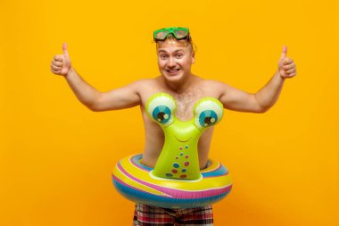 Sarı arka planda salyangoz ve dalış maskesi şeklinde lastik halkalı üstsüz bir adam. İzole et