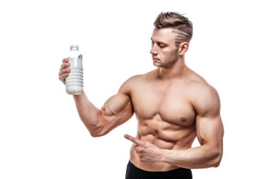 Elinde bir şişe süt, beyaz arka planda poz veren sportif vücutlu bir adam.