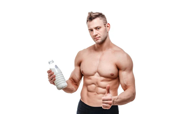 Una botella de leche en la mano, un hombre con cuerpo deportivo posando sobre un fondo blanco — Foto de Stock