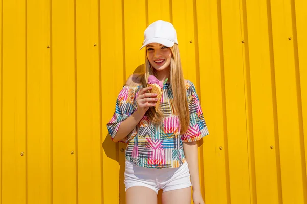 Outdoor mode portret van jonge hipster meisje met ijs op gele muur achtergrond — Stockfoto
