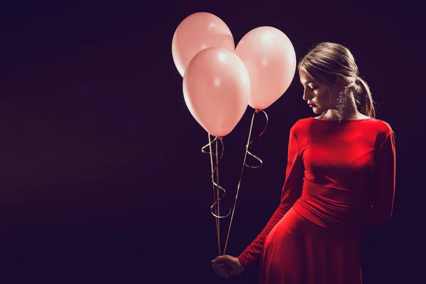 Mujer con un globo, mujer con una bola rosa sobre un fondo oscuro — Foto de Stock