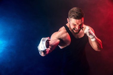 Sporcu Muay Thai boksörü siyah arka planda dumanla dövüşüyor. Spor konsepti