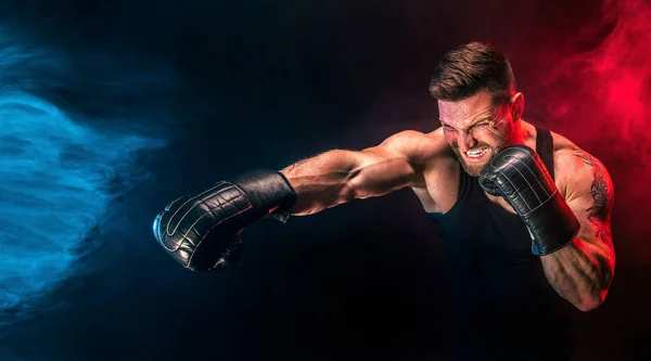 Бородатый татуированный спортсмен Муай тай боксер в черной майке и боксерских перчатках, дерущийся на темном фоне с дымом. — стоковое фото