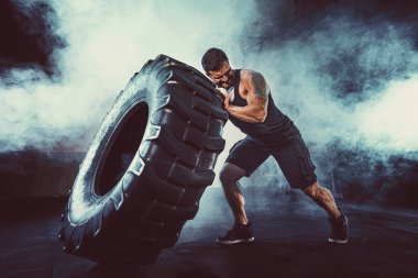 Vücut geliştirme eğitimi, sakallı güçlü sporcu, kaslı vücut, spor salonunda ağır tekerlekleri kaldırıyor.