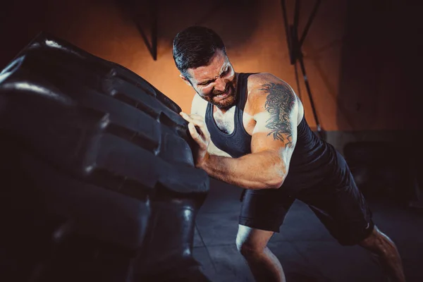 Testépítő tréning, szakállas erős sportoló izmos test emelés nehéz kerék tornaterem — Stock Fotó