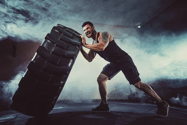 Vücut geliştirme eğitimi, sakallı güçlü sporcu, kaslı vücut, spor salonunda ağır tekerlekleri kaldırıyor. — Stok fotoğraf