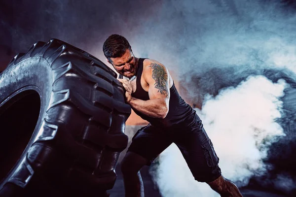 Bodybuilding-Training, bärtiger kräftiger Sportler mit muskulösem Körper, der schweres Rad im Fitnessstudio hebt — Stockfoto