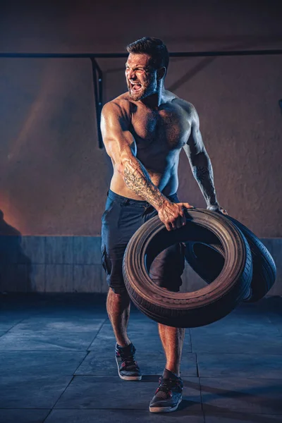 Bodybuilding training, bebaarde sterke sporter met gespierd lichaam tillen zwaar wiel in de sportschool — Stockfoto