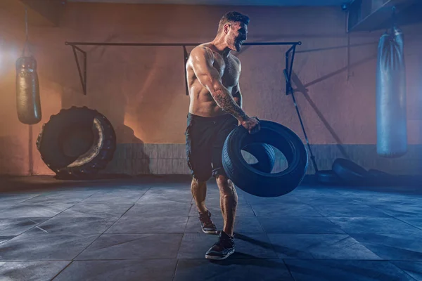 Bodybuilding-Training, bärtiger kräftiger Sportler mit muskulösem Körper, der schweres Rad im Fitnessstudio hebt — Stockfoto