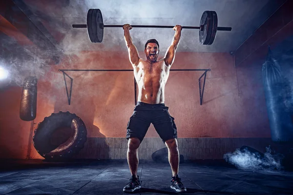 Muscular fitness hombre haciendo deadlift una barra sobre su cabeza en el moderno gimnasio. Entrenamiento funcional. Ejercicio arrebatado — Foto de Stock