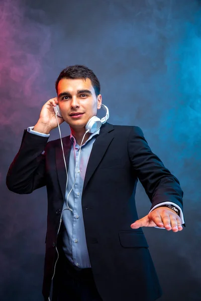 Retrato de homem com fones de ouvido no fundo escuro com fumaça. Estúdio — Fotografia de Stock