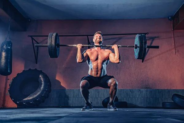 Een gespierde fitnessman duwt een lange halter over zijn hoofd in een modern fitnesscentrum. Functionele opleiding. Snatch oefening — Stockfoto