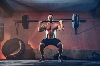 Kaslı fitness adamı garajında halterle kafasına vuruyor, kendini soyutluyor. İşlevsel eğitim. Kapma egzersizi.