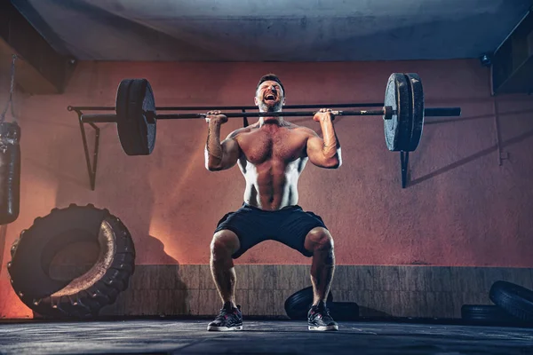 Muscular fitness man doing push a barbell over his head in his garage, selfisolation. Functional training. Snatch exercise — Stock Photo, Image