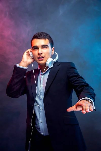 Retrato de homem com fones de ouvido no fundo escuro com fumaça. Estúdio — Fotografia de Stock