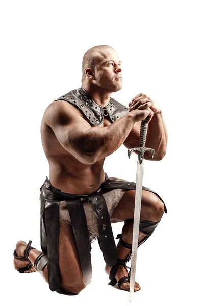 Ciężki barbarzyńca w skórzanym kostiumie z mieczem. Portret łysego gladiatora. Zdjęcia studyjne. Izolacja na białym tle — Zdjęcie stockowe