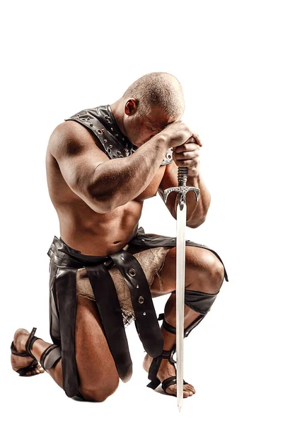 Severe barbarian in leather costume with sword. Portrait of balded muscular gladiator. Studio shot. Isolated on white background — Stock Photo, Image
