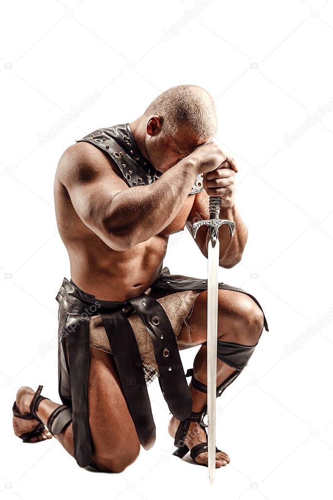 Severe barbarian in leather costume with sword. Portrait of balded muscular gladiator. Studio shot. Isolated on white background