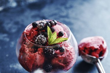 Dondurma, kiraz, ahududu, çilek, kızılcık, kırmızı şerbet, kepçe, siyah taş arka plan. kopyala, metin uzayı