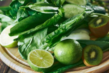 Taş tahtadaki malzemelerle harmanlanmış yeşil smoothie, ahşap masa.