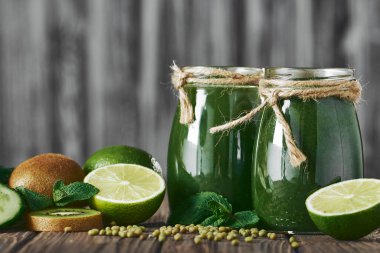 Taş tahtadaki malzemelerle harmanlanmış yeşil smoothie, ahşap masa.