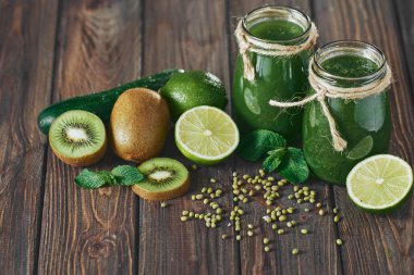 Taş tahtadaki malzemelerle harmanlanmış yeşil smoothie, ahşap masa.