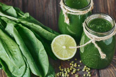 Taş tahtadaki malzemelerle harmanlanmış yeşil smoothie, ahşap masa.