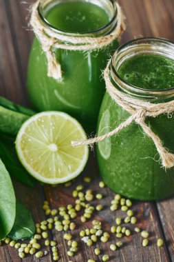 Taş tahtadaki malzemelerle harmanlanmış yeşil smoothie, ahşap masa.