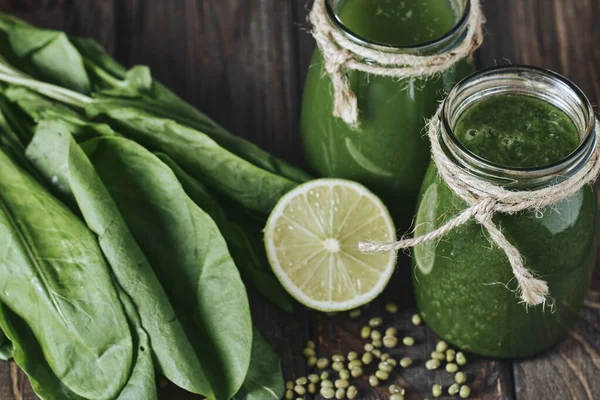 Taş tahtadaki malzemelerle harmanlanmış yeşil smoothie, ahşap masa.