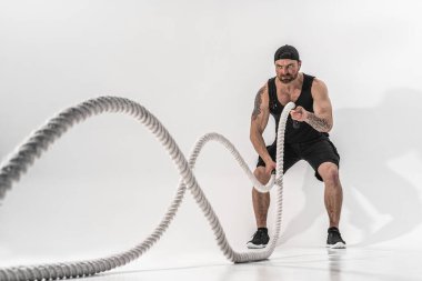 Çekici kaslı adam ağır iplerle çalışıyor. Fotoğraf: