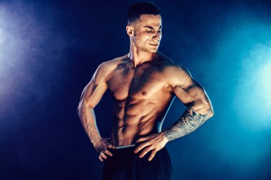 Stüdyoda kaslarını esneten atletik bir adam.