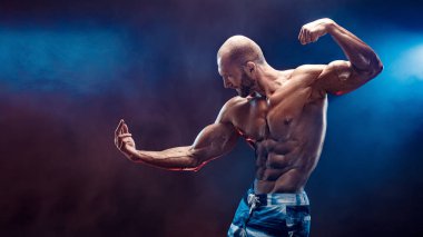 Stüdyoda siyah arka planda poz veren yakışıklı güçlü vücut geliştirici.