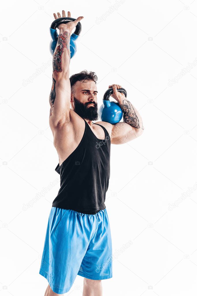 Muscular tattooed bearded male athlete bodybuilder workout with